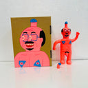 Neon pink painted soft vinyl figure of a nude man with glasses. He is balding with some facial hair and has a blue tipped penis atop his head. His nipples are blue and his own penis is also blue tipped. One of his hands is formed into a peace sign.