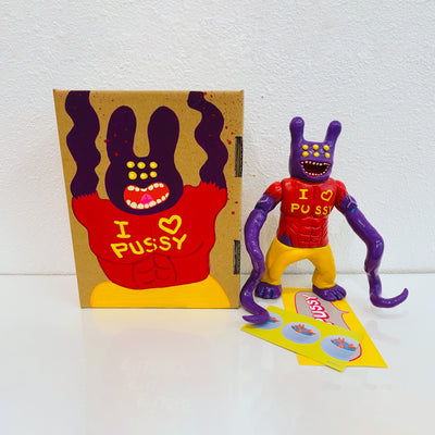Purple painted soft vinyl figure, with 6 yellow eyes, a wide open mouth smile and two bunny like ears. The figure is muscular and wears a red shirt that says "I heart pussy" with two long tentacles as arms.
