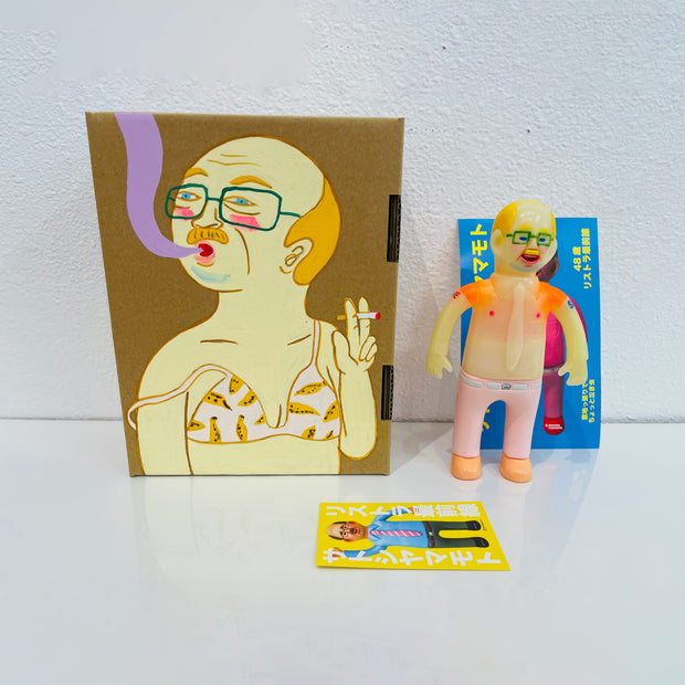 Semi translucent soft vinyl figure of a business man, shirtless in light pink slacks. He stands next to a painted box.