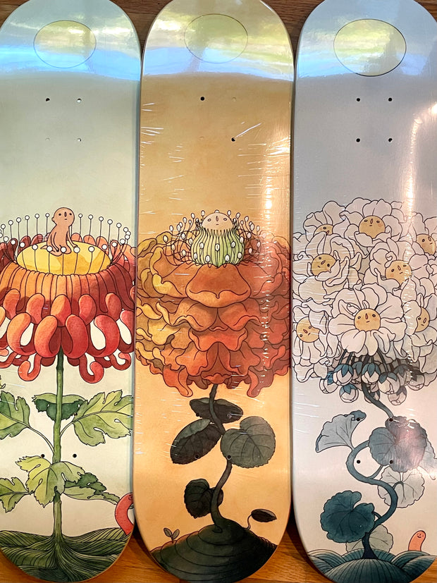 3 skateboard decks with floral themed illustrations.