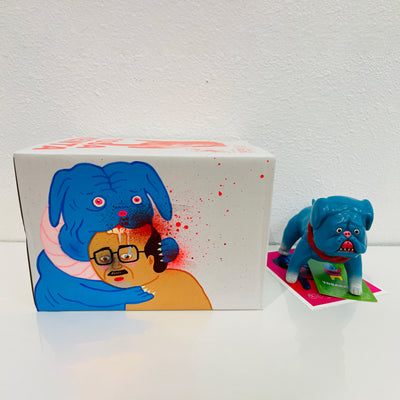Blue soft vinyl figure of a pitbull type dog, with a red collar and white paws. It stands in front of its product packaging with a few notecard underneath its box.