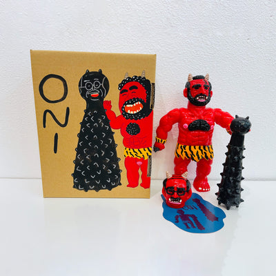 Red soft vinyl figure of a demon man, with muscles and horns atop his head. He has a large black spiked club and a human head at his feet. He stands next to a painted box.