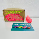 Small semi transparent glittery pink figurine shaped like a poop. It sits next to a painted box.