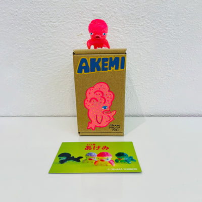 Small pink soft vinyl figure of an octopus creature, with a large head and small limbs. It stands on a painted box.