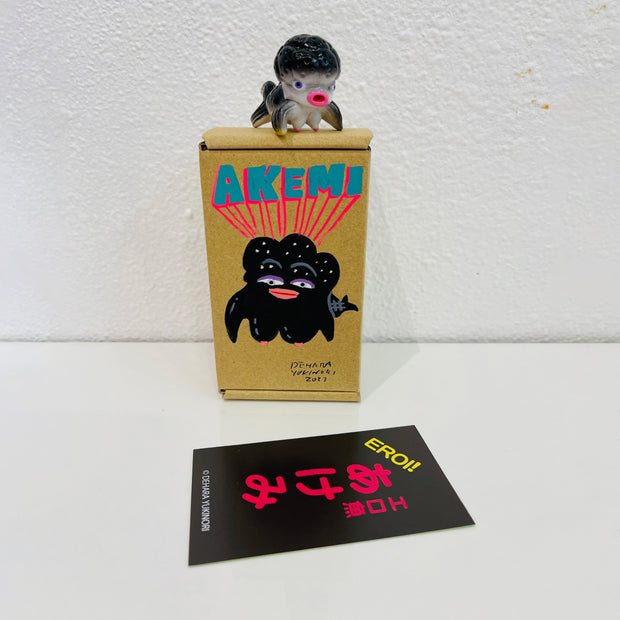 Small black and grey soft vinyl figure of an octopus creature, with a large head and small limbs. It stands on a painted box.