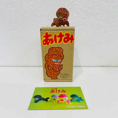 Small brown soft vinyl figure of an octopus creature, with a large head and small limbs. It stands on a painted box.
