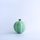 Small green round bottomed jar with a lid, painted like a melon with white striping and a small leaf on the top of the lid, like a mini handle.