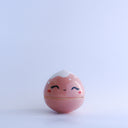 Small pink round bottomed jar with a lid. The lid has white coloring at the very top and a drawn on, cute face with rosy cheeks.