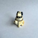Ceramic sculpture of a white dog with black floppy ears and a black spiked collar. Its body has functionality of a teapot.