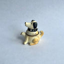 Ceramic sculpture of a white dog with black floppy ears and a black spiked collar. Its body has functionality of a teapot.