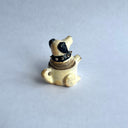 Ceramic sculpture of a white dog with black floppy ears and a black spiked collar. Its body has functionality of a teapot.