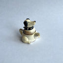 Ceramic sculpture of a white dog with black floppy ears and a black spiked collar. Its body has functionality of a teapot.
