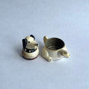 Ceramic sculpture of a white dog with black floppy ears and a black spiked collar. Its body has functionality of a teapot.