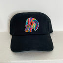 A black baseball cap featuring a colorful felted wool skull on the front, displayed against a plain white wall.