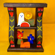 Decorative wooden shelf with colorful floral themed paintings along the side. Small, cute wooden characters are on the shelves like trinkets.