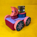 Colorful wooden toy car with a pink character with a moon shaped head on top and a light in the back of the car.