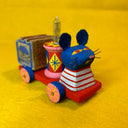 Colorful toy mouse riding on a cart with a retro wooden block as a caboose and a light in the middle.