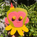 Colorful die cut sculpture of a pink monkey with green hair and eyes that move.