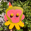 Colorful die cut sculpture of a pink monkey with green hair and eyes that move.