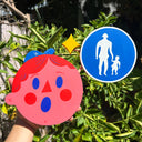 Die cut sculpture of a pink cartoon character's head, wearing a tiny LA cap with a surprised expression. Attached to him is a cross walk sign.