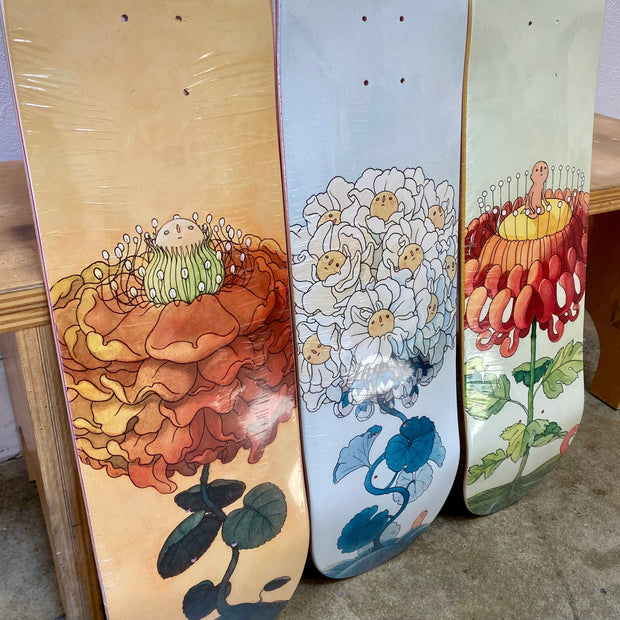 3 skateboard decks with floral themed illustrations.