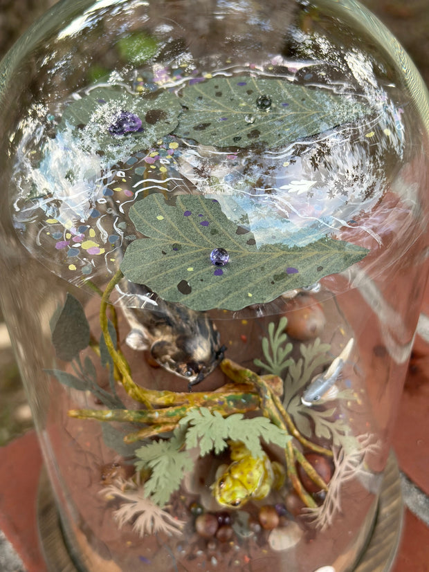 Mixed media diorama of an underwater scene, with a large scary looking fish swimming over a mound of land. Burrowed into the side of the mound is a small frog, hiding from the fish.