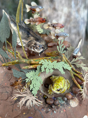 Mixed media diorama of an underwater scene, with a large scary looking fish swimming over a mound of land. Burrowed into the side of the mound is a small frog, hiding from the fish.