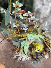 Mixed media diorama of an underwater scene, with a large scary looking fish swimming over a mound of land. Burrowed into the side of the mound is a small frog, hiding from the fish.