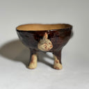 Glossy dark brown ceramic bowl with 3 dog heads jutting out, all sharing a bowl body with 4 legs. 