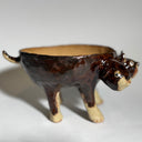 Glossy dark brown ceramic bowl with 3 dog heads jutting out, all sharing a bowl body with 4 legs. 