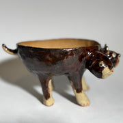 Glossy dark brown ceramic bowl with 3 dog heads jutting out, all sharing a bowl body with 4 legs. 