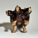 Glossy dark brown ceramic bowl with 3 dog heads jutting out, all sharing a bowl body with 4 legs. 