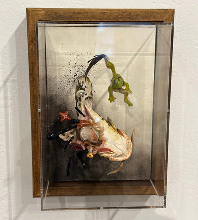 Mixed media diorama scene of a small green frog slaying a large monstrous fish with a knife, splaying the fish's guts over the scene.