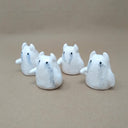 4 small white ceramic ghosts with little devil horns, all crying watercolor tears. They have no facial features other than black eyes and minimal body features, only one arm that extends outwards.