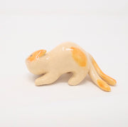  Ceramic sculpture of cream colored with orange spots cat on all fours, leaning with its head tilted as though ready to be petted. It has 2 tails.