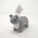 Ceramic sculpture of a gray cat with simplistic body features and a drawn on eyes and whiskers. Hovering atop its back is a small white ghost, with watercolor style tears.