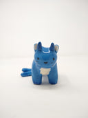 Small blue ceramic sculpture of a cat with 2 tails and horns coming out atop its head. It has simplistic body features and a drawn on face.