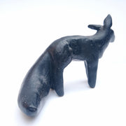 Dark blue sculpture of a fox like animal, with pointed ears and a large bushy tail. It has no facial features and its body shapes are minimally rendered.