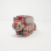 Ceramic sculpture of the Catbus from My Neighbor Totoro with muted colorings and a simplistic drawn on face.