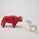 2 ceramic sculptures: one of a white unicorn with a light blue mane and the other of a large red bull. They stand facing one another.