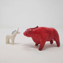 2 ceramic sculptures: one of a white unicorn with a light blue mane and the other of a large red bull. They stand facing one another.