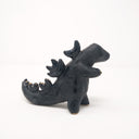 Ceramic sculpture of a dark blue abstract Godzilla figure, with abstract spikes on its back, no facial features, and one arm extended out.