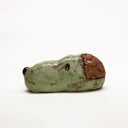 Ceramic sculpture of a green dog head, akin to Snoopy without the ears. His brain is exposed and can be removed to reveal the inside.