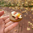 Small figurine of a dog on a round base held by a hand with a blurred outdoor background.