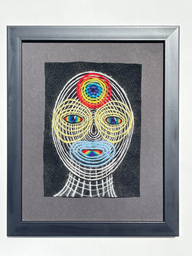 Framed artwork of colorful concentric circles portrait of a head on a black background