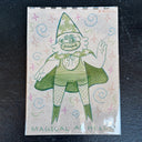 A whimsical hand-drawn green character with a pointed hat, surrounded by pastel swirls and starbursts on a beige background, photographed on a dark textured surface.