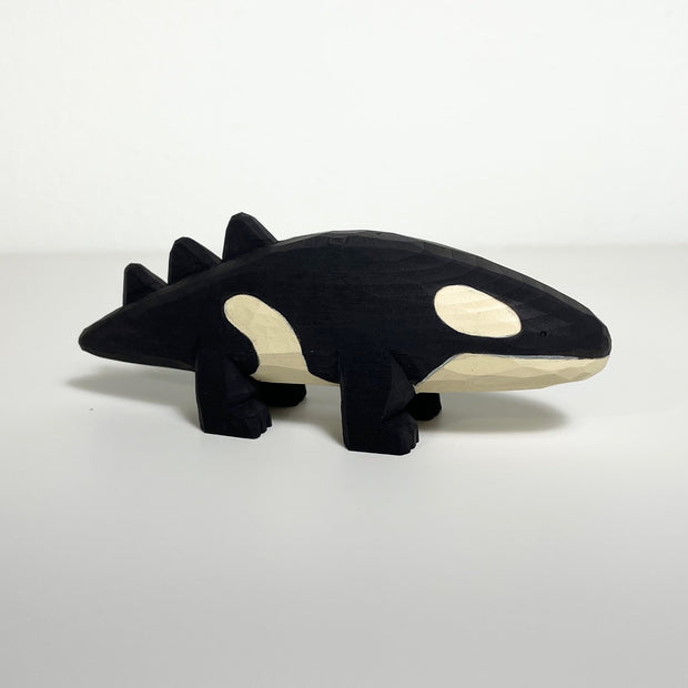 Carved wooden sculpture of an orca whale with 4 feet like a quadruped.
