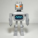 Carved and assembled wooden sculpture of a robot with a cat like face with bright yellow and red eyes and rounded ears atop its head. Its stomach contains a screen that displays a blue wavelength.