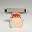 Carved and painted wooden sculpture of a hammerhead shark with a cartoon like expression, eyes looking off to the side and a downturned open mouth. 