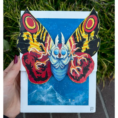Painting of Mothra, with bright red, yellow and black wings and many clawed feet coming out of its body. It flies over a blue town, covered in a thin white web.
